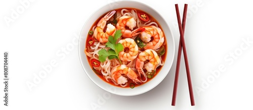 A top view of a spicy Tom Yum Kung instant noodle dish served in a red bowl on a white background accompanied by chopsticks. Copy space image. Place for adding text and design