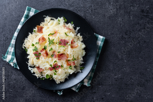 Slovak potato dumplings halusky with steamed sauerkraut and bacon on black background. Top view. Copy space photo