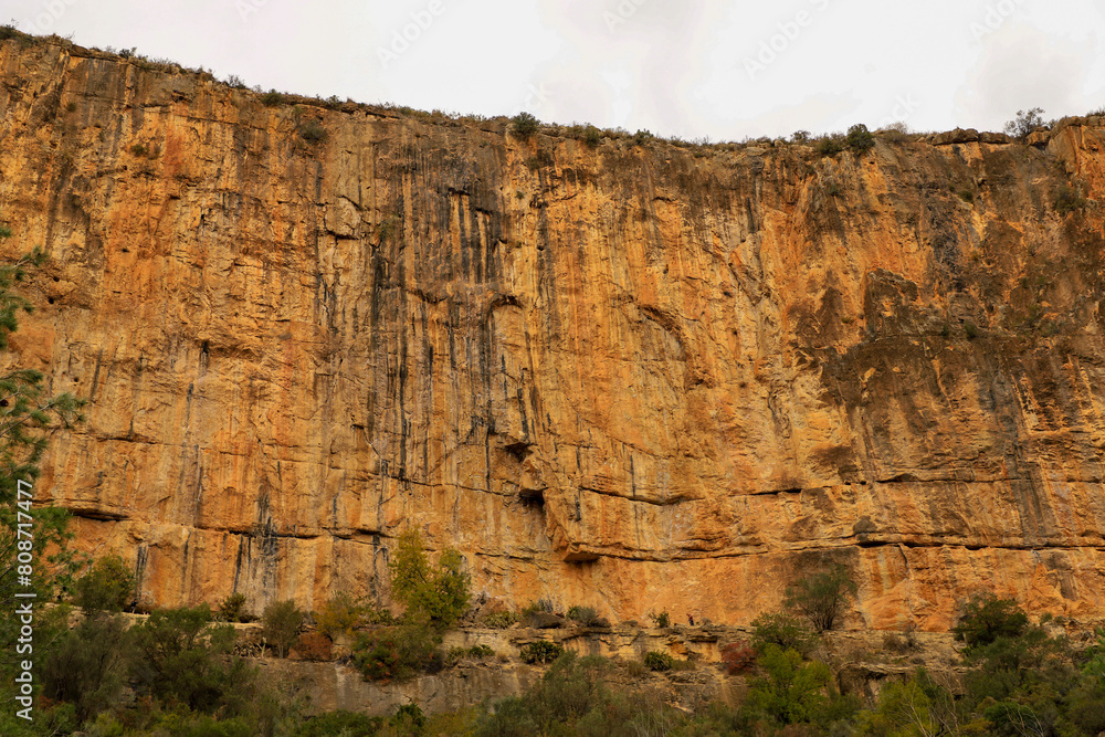 Large reddish rock wall with climbing routes for mountaineers in the city of Chulilla,Valencia,Spain