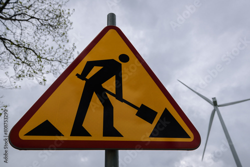 
ROADWORKS AREA - Worning sign on the trees and wind mill background 