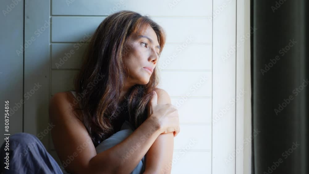 Depressed Asian mature woman sitting in dark bedroom and hugging herself with sadness. Loneliness middle aged woman living alone with negative emotion. People mental health and life problem concept. Depressed Asian mature woman sitting in dark bedroom and hugging herself with sadness. Loneliness middle aged woman living alone with negative emotion. People mental health and life problem concept.