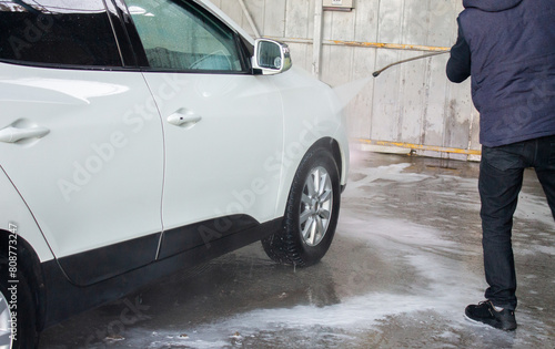 Closeup of male driver washing his car with contactless high pressure water jet in self service car wash © яна винникова