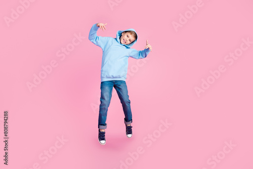 Full body photo of cheerful carefree schoolkid jump hood head empty space isolated on pink color background