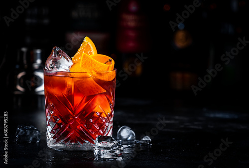 Coffee negroni red cocktail drink with dry gin, vermouth and bitter, espresso, liqueur, orange and ice. Black bar counter background © 5ph