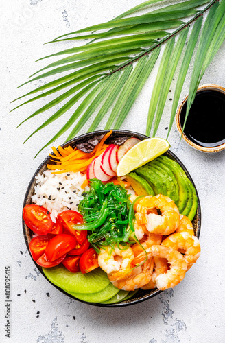 Balanced food nutrition. Poke bowl with shrimp, rice, avocado, vegetables and chuka salad, white table background, top view