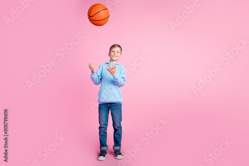 Full body portrait of positive small boy arms throw catch basketball empty space isolated on pink color background