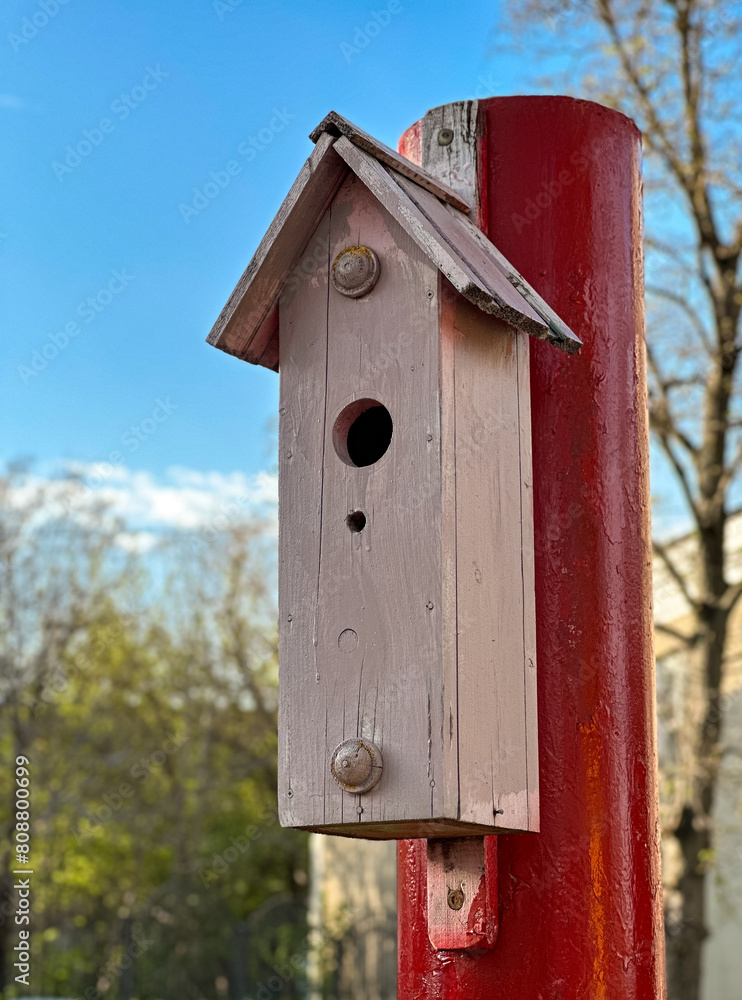 A wooden birdhouse on a pole in the park in summer. An outdoor bird house . A wooden birdhouse on a pole in the park in summer. An outdoor bird house .