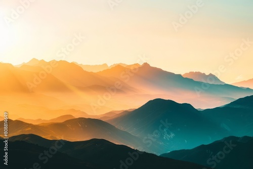 A mountain range at sunrise  with the peaks illuminated in gold against the shadowed valleys