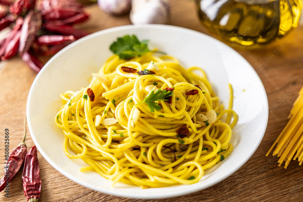 A plate of spaghetti aglio e olio with chili flakes, fresh parsley, garlic, and a drizzle of extra virgin olive oil