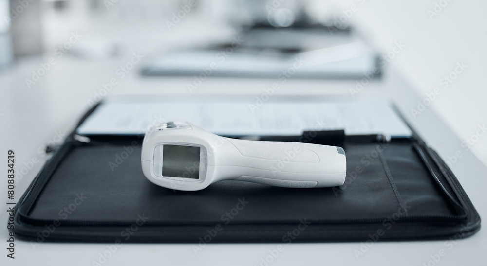 Medical, digital and thermometer gun in office of hospital with clipboard for data, information and record of patient symptoms. Document, clinic and equipment for safety check with healthcare Medical, digital and thermometer gun in office of hospital with clipboard for data, information and record of patient symptoms. Document, clinic and equipment for safety check with healthcare
