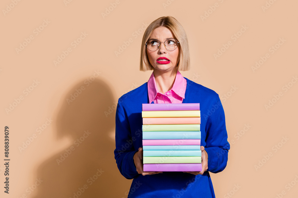 Portrait of minded unsatisfied lady hold pile stack book look empty space isolated on beige color background Portrait of minded unsatisfied lady hold pile stack book look empty space isolated on beige color background