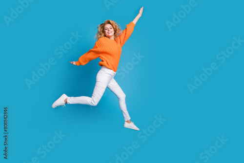 Photo of positive funky crazy woman wear trendy orange clothes walk empty space isolated on blue color background