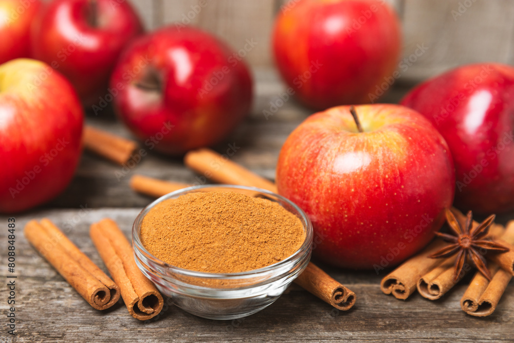 Apples with cinnamon on a textured wooden background. Fragrant red spiced apples with cinnamon sticks and star anise. Apple slices with spicy spices. Place for text. Copy space. Harvesting. Fruits. 