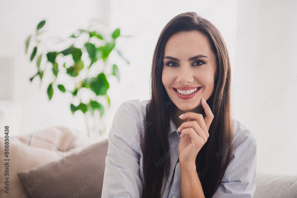 Photo of thoughtful dreamy lady dressed blue shirt sitting sofa smiling finger chin indoors house room Photo of thoughtful dreamy lady dressed blue shirt sitting sofa smiling finger chin indoors house room