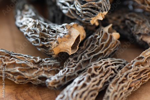 Dry Morel Mushrooms on Wooden Platter. Close-up of textured morel mushrooms, artfully arranged on a rustic wooden platter, emphasizing their unique structure.