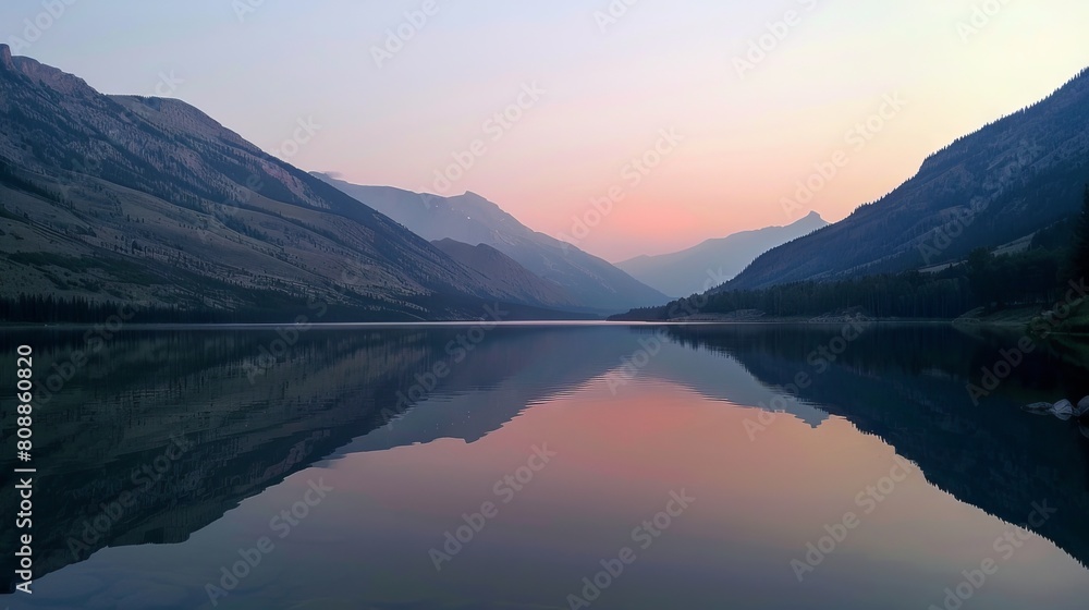In the serene embrace of a mountainous landscape, a tranquil lake reflects the vibrant colors of dawn, creating a peaceful and picturesque scene. 