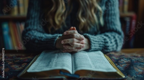 Close-up of a Person Praying with Hands Clasped Over an Open Bible