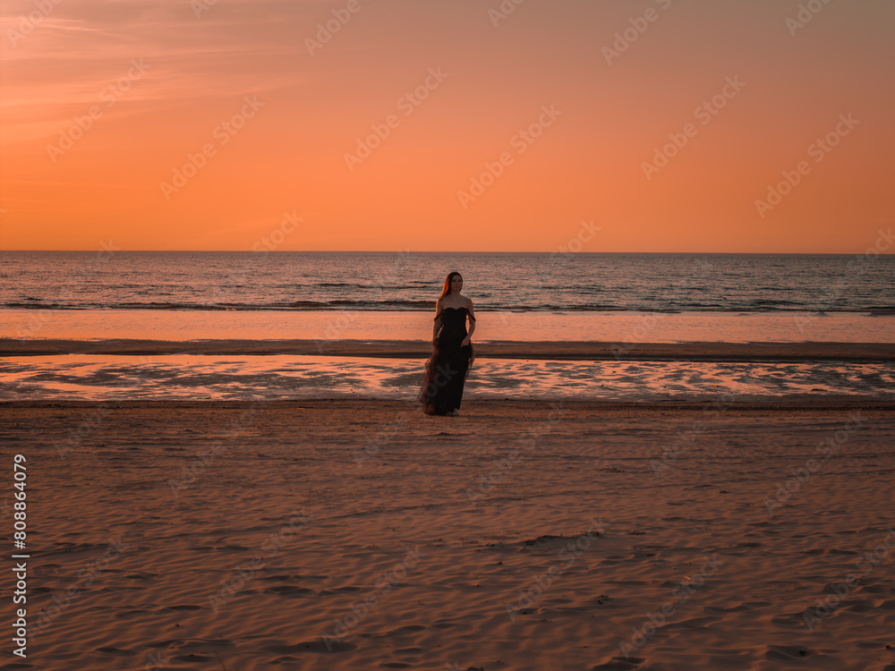 Φωτογραφία Happy beautiful woman in a long black dress enjoying beautiful sunset on the Beach in California