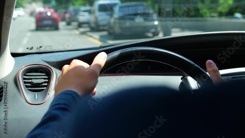 Male hands on steering wheel inside the car driving and looking at road in city. Over shoulder view of man driver drives an vehicle. Close up shot. Traffic on background. Travel concept © Nataliya