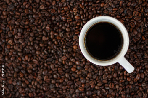Black coffee in a white cup on a background of coffee beans.