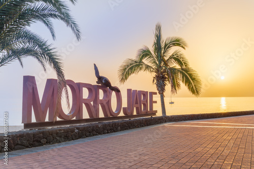 Morro Jable resort signage with palm letters outdoors on the coast on Fuerteventura island at sunset. © cristianbalate