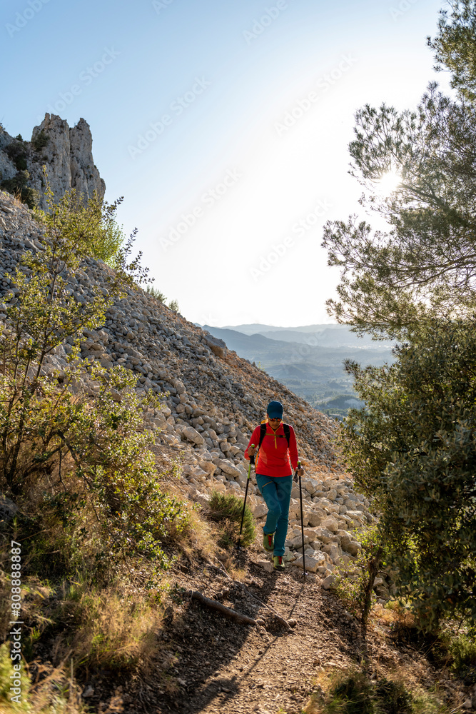 Woman backpacker on the hiking path to Frares de Serrella mountain range on Costa Blanca, Quatretondeta , Alicante, Spain - stock photo