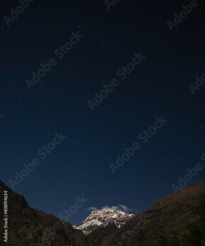 Minimalistic night landscape of the Greater Hansa mountain peak at night against the backdrop of a clear starry sky, a cold mountain with snow and glaciers in the evening