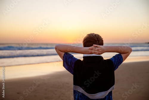 Happy cheerful teenager standing on beach at sunset. happy preteen boy smiling at the camera. Kid on family vacation at the sea.