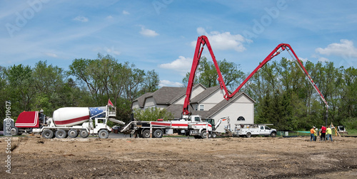 Concrete Truck and Boom Pump Truck Pumping Concrete at Construction Site