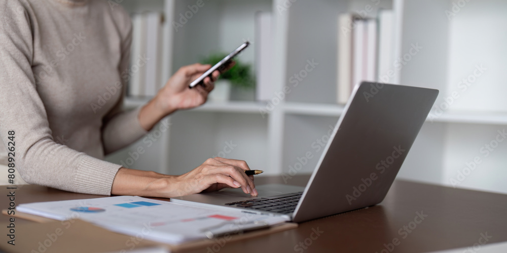 Businesswoman using laptop computer and working at office with calculator document on desk, doing planning analyzing the financial report, business plan investment, finance analysis concept Businesswoman using laptop computer and working at office with calculator document on desk, doing planning analyzing the financial report, business plan investment, finance analysis concept