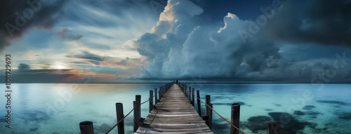 a serene wooden pier extending into a tranquil sea against a backdrop of a vibrant sunset and an approaching storm photo