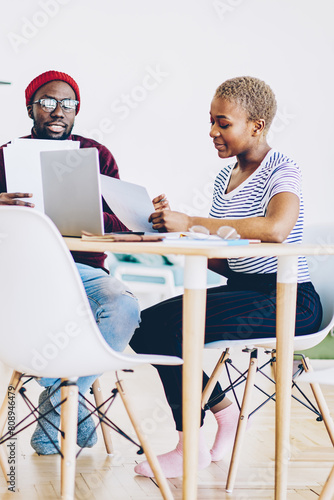 Young african american couple checking bills and receipts for paying online via application on laptop computer, dark skinned colleagues discussing ideas and making plans using modern technology