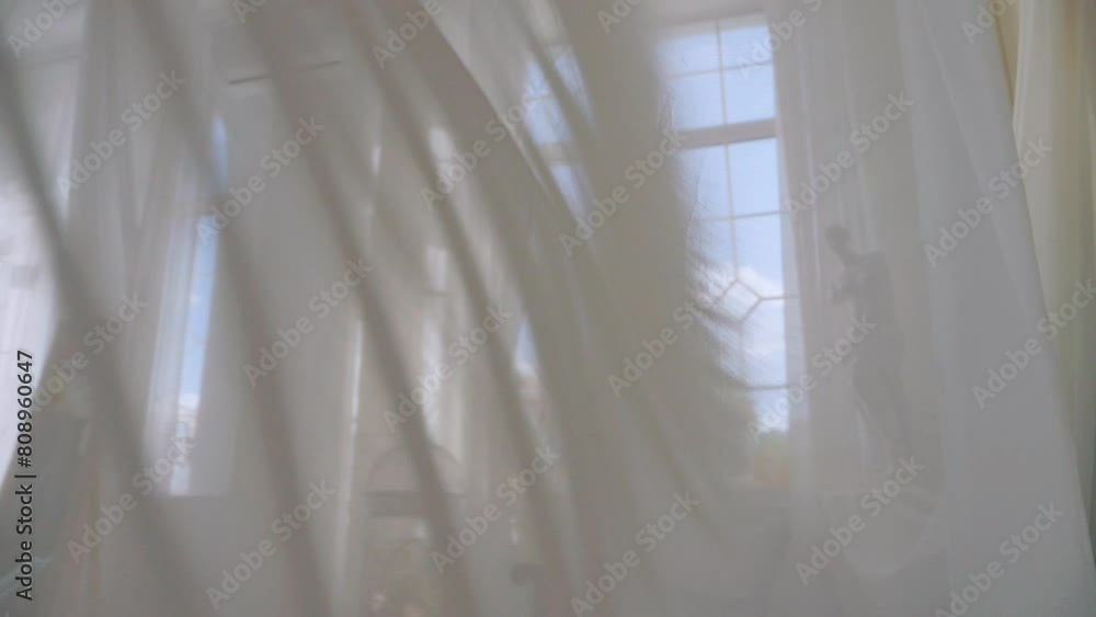 Bright room featuring billowing white curtains. Serene room with delicate birdcage and flowing white curtains. White transparent fabric flutters in the wind. Long white curtains in a bright studio. Sh Bright room featuring billowing white curtains. Serene room with delicate birdcage and flowing white curtains. White transparent fabric flutters in the wind. Long white curtains in a bright studio. Sh