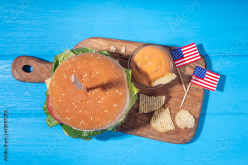 Tasty cheeseburger, chips and sauce with patriotic american flag. July 4th, Independence day picnic party food, usa themed  bbq hamburger copy space