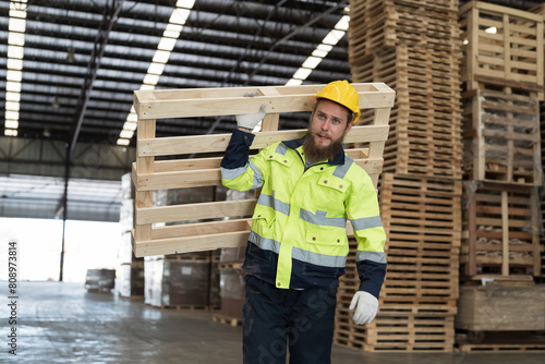 Male warehouse worker working and carrying wood pallet at wood warehouse photo