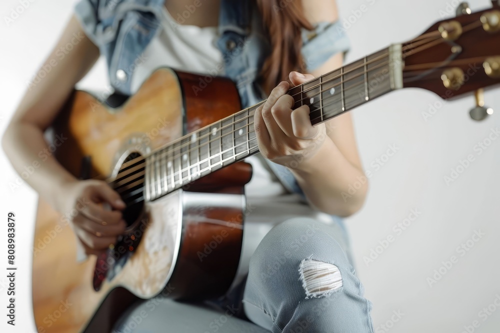 smiling woman playing acoustic guitar wearing jeans isolated on white background music concept photo
