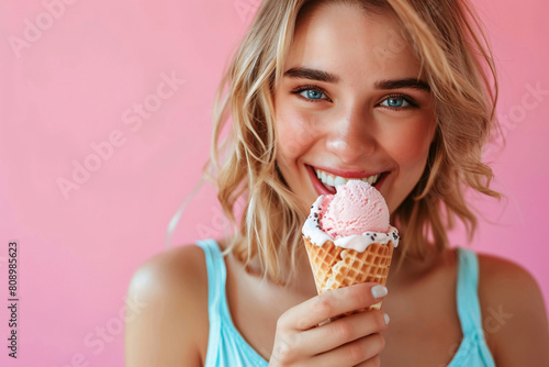 Young beautiful woman eating ice cream in waffle cone on pink background