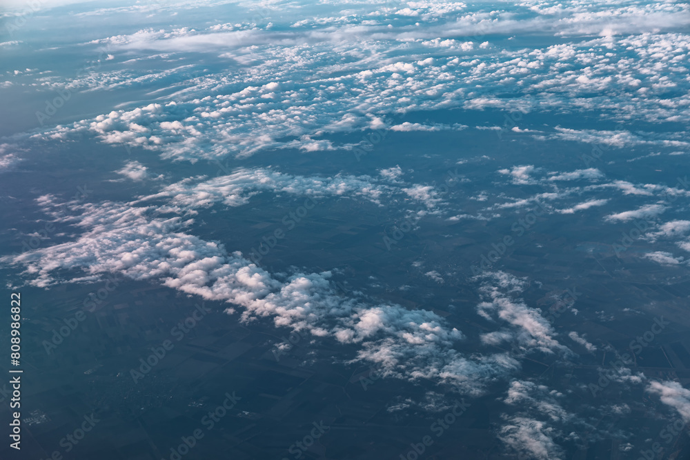 Clouds and sky over the Earth as seen through window of an aircraft, view from above