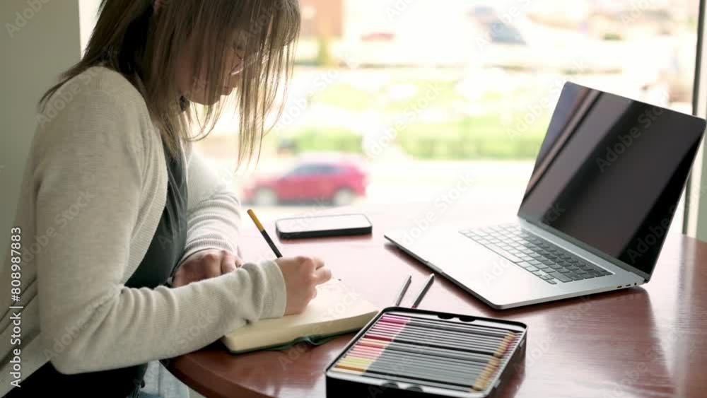 artist meticulously sketching in her notebook, with digital tools like laptop and smartphone within easy reach, illustrating the modern artist's workspace. artist meticulously sketching in her notebook, with digital tools like laptop and smartphone within easy reach, illustrating the modern artist's workspace.