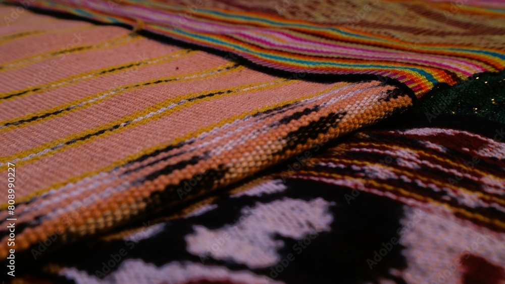 Close up side view handmade woven fabric with unique pattern from Indonesia, selective focus, multicolour textured textile background Close up side view handmade woven fabric with unique pattern from Indonesia, selective focus, multicolour textured textile background