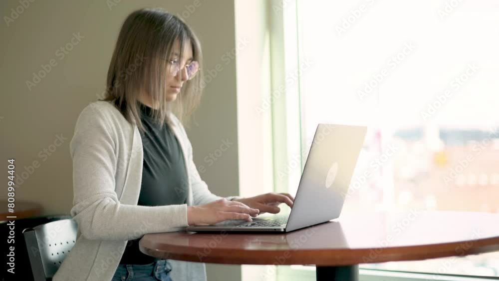 professional young woman with glasses works diligently on her laptop office setting natural light streaming through window integration of technology modern work life remote work business efficiency professional young woman with glasses works diligently on her laptop office setting natural light streaming through window integration of technology modern work life remote work business efficiency