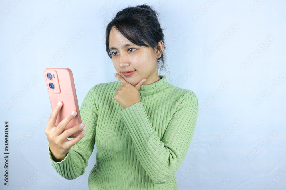 pensive expression of Asian woman holding smart phone on white background pensive expression of Asian woman holding smart phone on white background