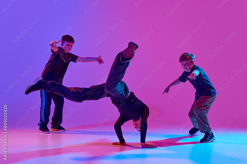 Dance battles. Dancer performing impressive headstand, breakdance moves mixed neon light against vibrant gradient background. Concept of sport and hobby, music, fashion and art, movement. Ad