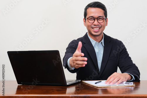 A recruiter staff smiling confidence while offering handshake during interview process