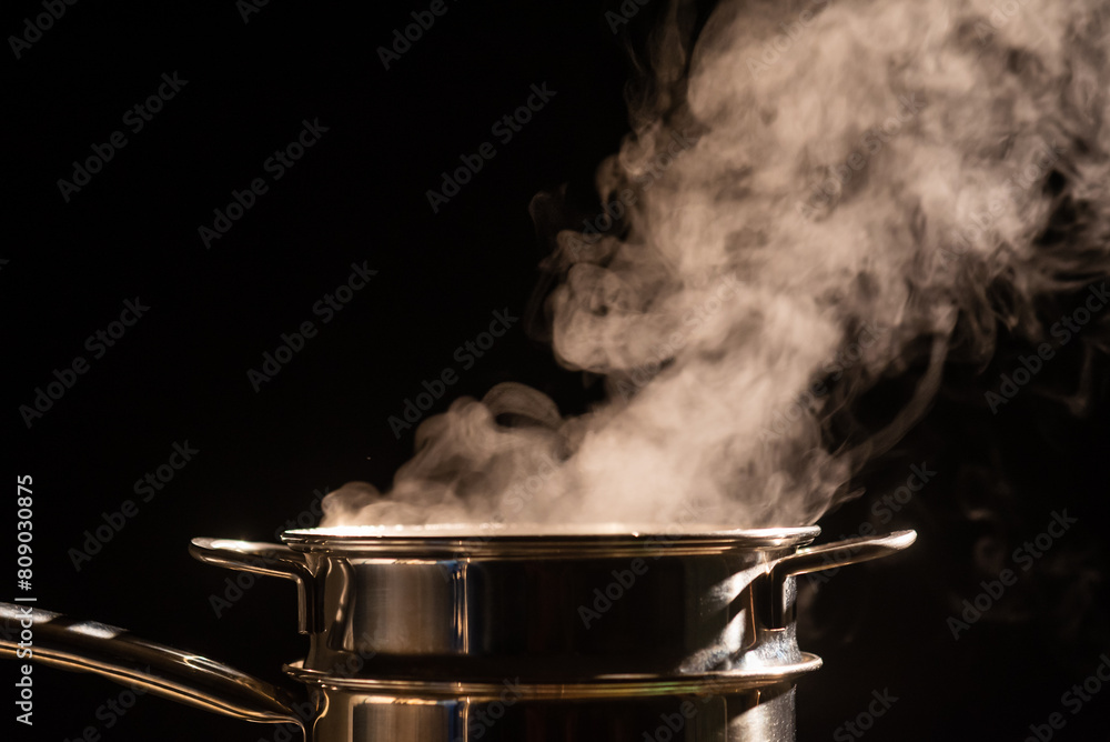 A boiling pot steams up as a chef cooking steam food in steam pot in a restaurant. A boiling pot steams up as a chef cooking steam food in steam pot in a restaurant.