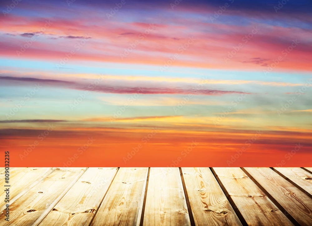 Wooden table on sky background and sunset light	
