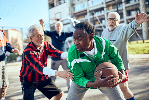 Senior men playing basketball in outdoor court photo