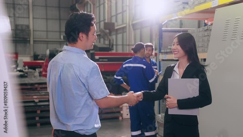 Asian businessman manager leader and woman assistant holding document file and shaking hands after reach an agreement together at metal factory. Industrial metal concept.