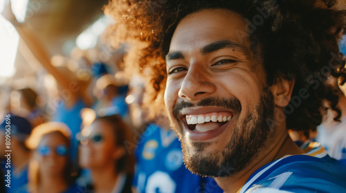 Joyful African American male sports fan in blue jersey celebrating at a stadium during a football game, depicting excitement and teamwork Related concepts: sports events, fan culture photo