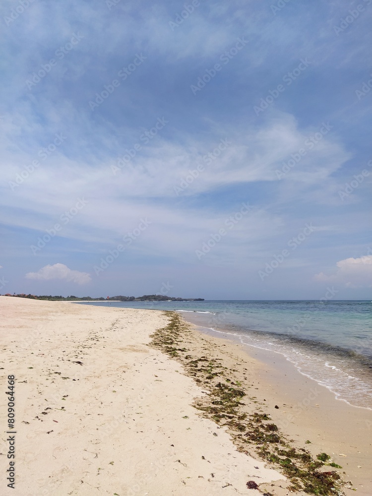 The ocean shore in Bali, clouds in the blue sky, sunny clear day, Bali, Indonesia The ocean shore in Bali, clouds in the blue sky, sunny clear day, Bali, Indonesia